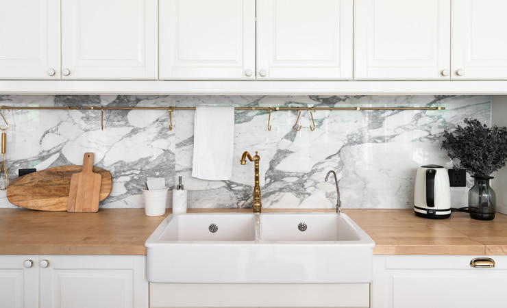 A kitchen with white cabinetry and a double sink.